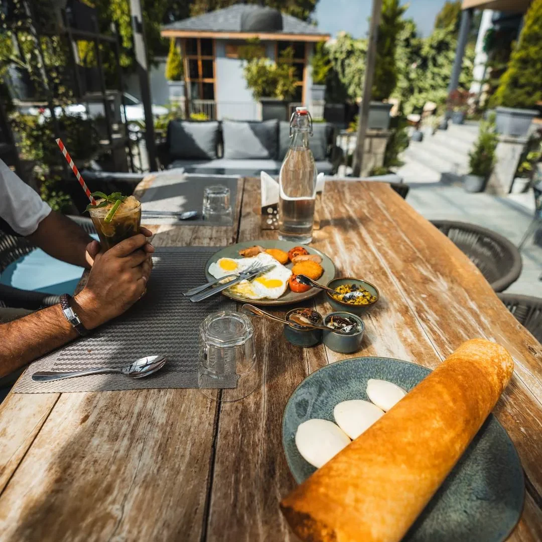 Brunch table with dosa, eggs and drinks on the Fatoosh terrace