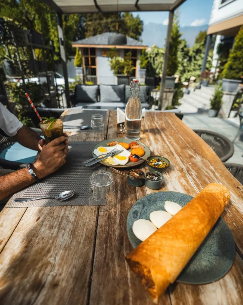 Brunch table with dosa, eggs and drinks on the Fatoosh terrace
