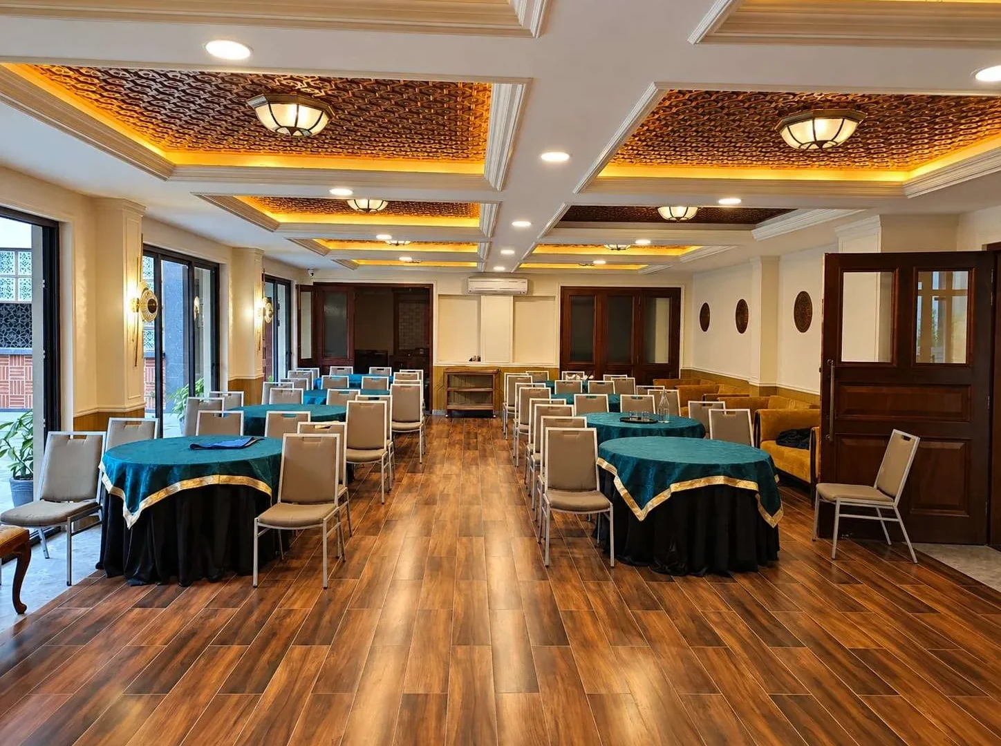 Banquet hall set with round tables under carved ceilings