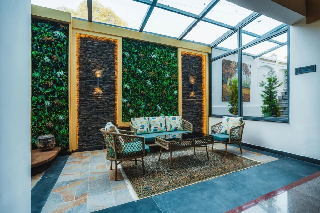 Glass-roofed atrium lounge with a green wall and cane seating