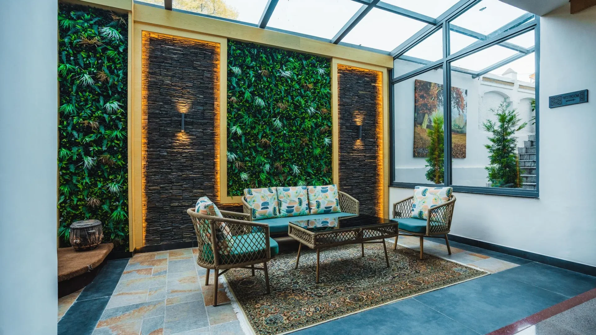Glass-roofed atrium lounge with a green wall and cane seating