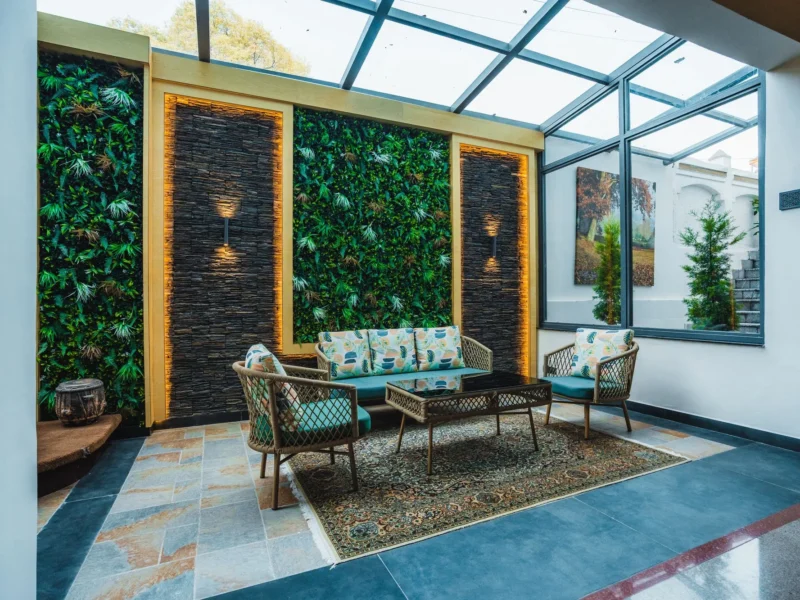 Glass-roofed atrium lounge with a green wall and cane seating