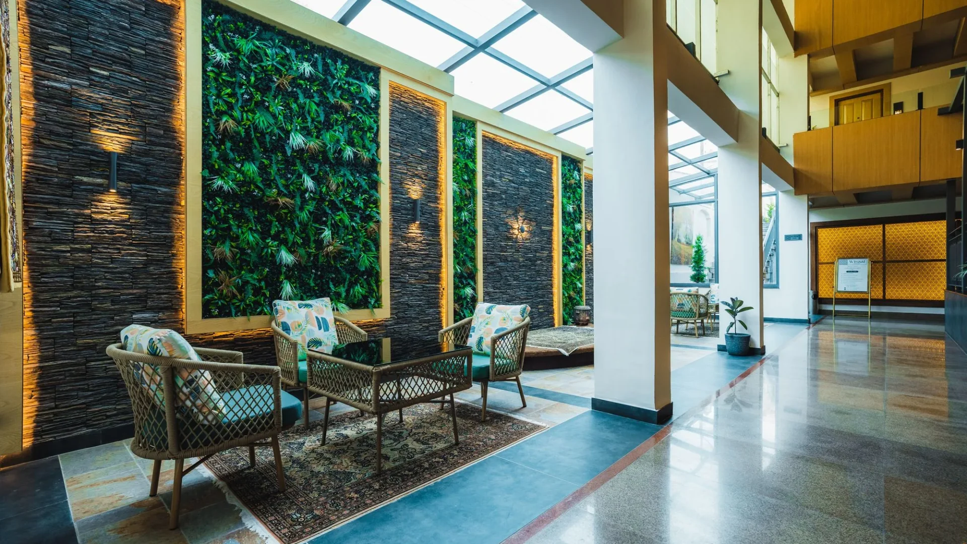 Seating beside a green wall under the glass roof of the atrium