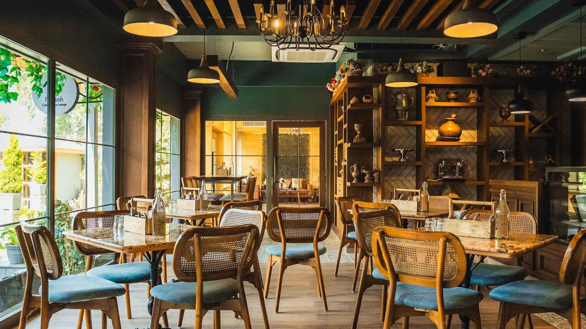 Fatoosh Café with wooden shelves, chandeliers and tables laid for guests
