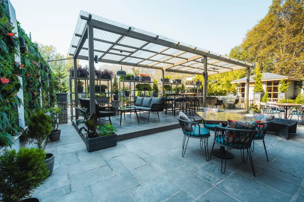 Covered outdoor seating area with plants at Fatoosh Café